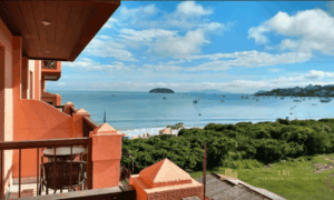 Vista panorâmica da sacada de um apartamento no Jurerê Beach Village mostrando o mar azul e a natureza preservada.
