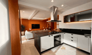 Bancada da cozinha gourmet em quartzo escuro integrada visualmente com a sala de estar ampla.