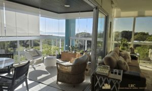Integração entre a sala de estar e a sacada gourmet com vista para o mar.