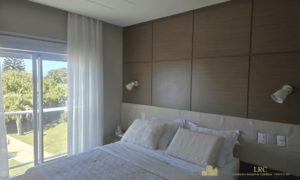 Suíte principal com cama de casal, iluminação natural e marcenaria.