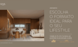 Sala de estar aconchegante com sofá claro, mesa de jantar redonda de madeira com quatro cadeiras, painéis de madeira na parede e cozinha ao fundo.